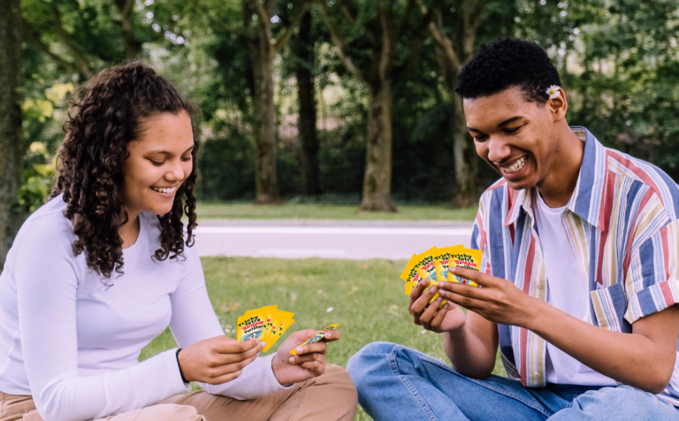 A couple playing Triple Tongue Twister card game outdoors